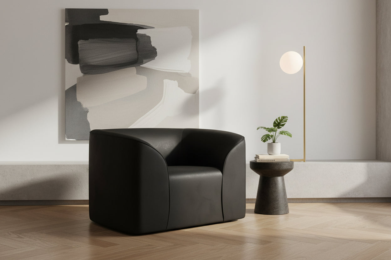 Black armchair in a modern room setting with a coffee table and an abstract painting on the wall